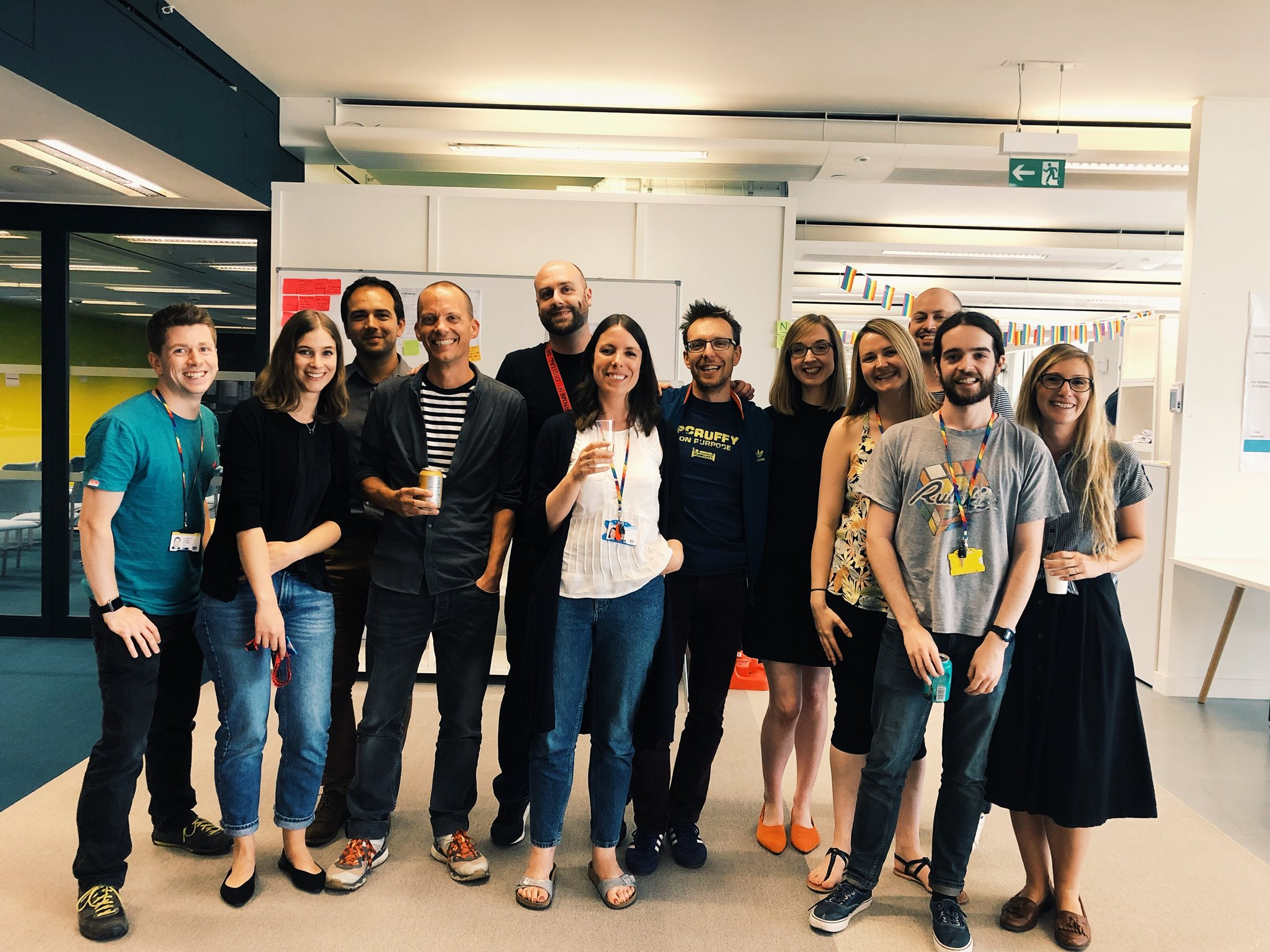 A smiling photo of 12 members of the gov uk design system team on launch day holding glasses of prosecco